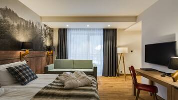 A hotel room with a bed, a desk, a chair, a television, and a large window with curtains.