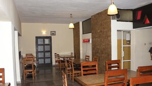 Ein Restaurant mit Holztischen und -stühlen, einer schwarzen Tür und einem roten Schild an der Wand.
