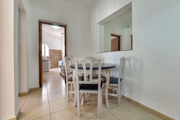 A hallway with a dining area featuring a round table and four chairs. A large mirror hangs on the wall.