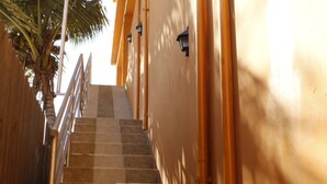 A staircase with a handrail leading up to a door with a light fixture.