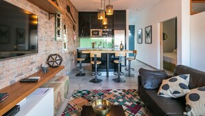 A modern living room with a leather sofa, a colorful rug, and a kitchen area with bar stools and a central island. - Merc Porto Ribeira's Up place (Porto)