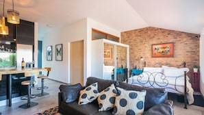 A modern living space with a kitchen area, a dining table, and a bed with a brick wall backdrop. - Merc Porto Ribeira's Up place (Porto)