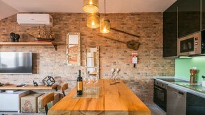A modern kitchen with a wooden island, built-in appliances, and a brick wall. - Merc Porto Ribeira's Up place (Porto)