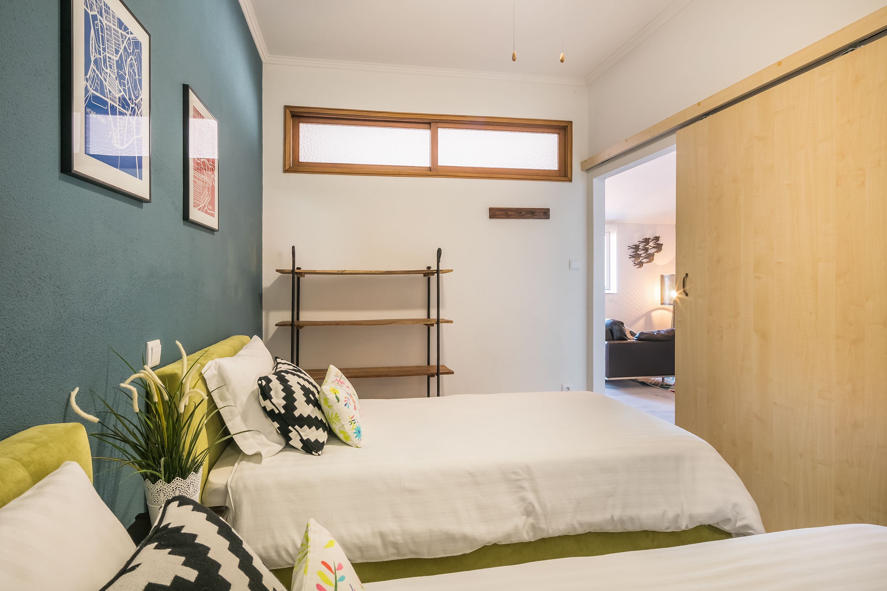 A bedroom with two beds, a window, and a wooden wardrobe.