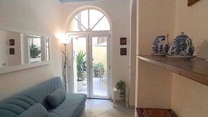 A living room with a sofa, a dining area with a table and decorative items, and a view of the outside through a glass door. - APARTMENT CLOSE TO THE CATHEDRAL & RAILWAY STATION,WI-FI (Firenze)