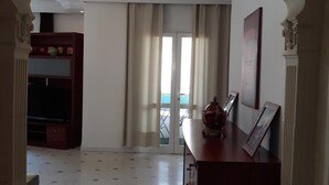 Un interior con suelo de baldosas, un armario de madera y un balcón con vistas.