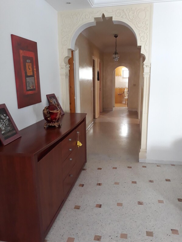 A hallway with a wooden cabinet, framed pictures, and a decorative urn.