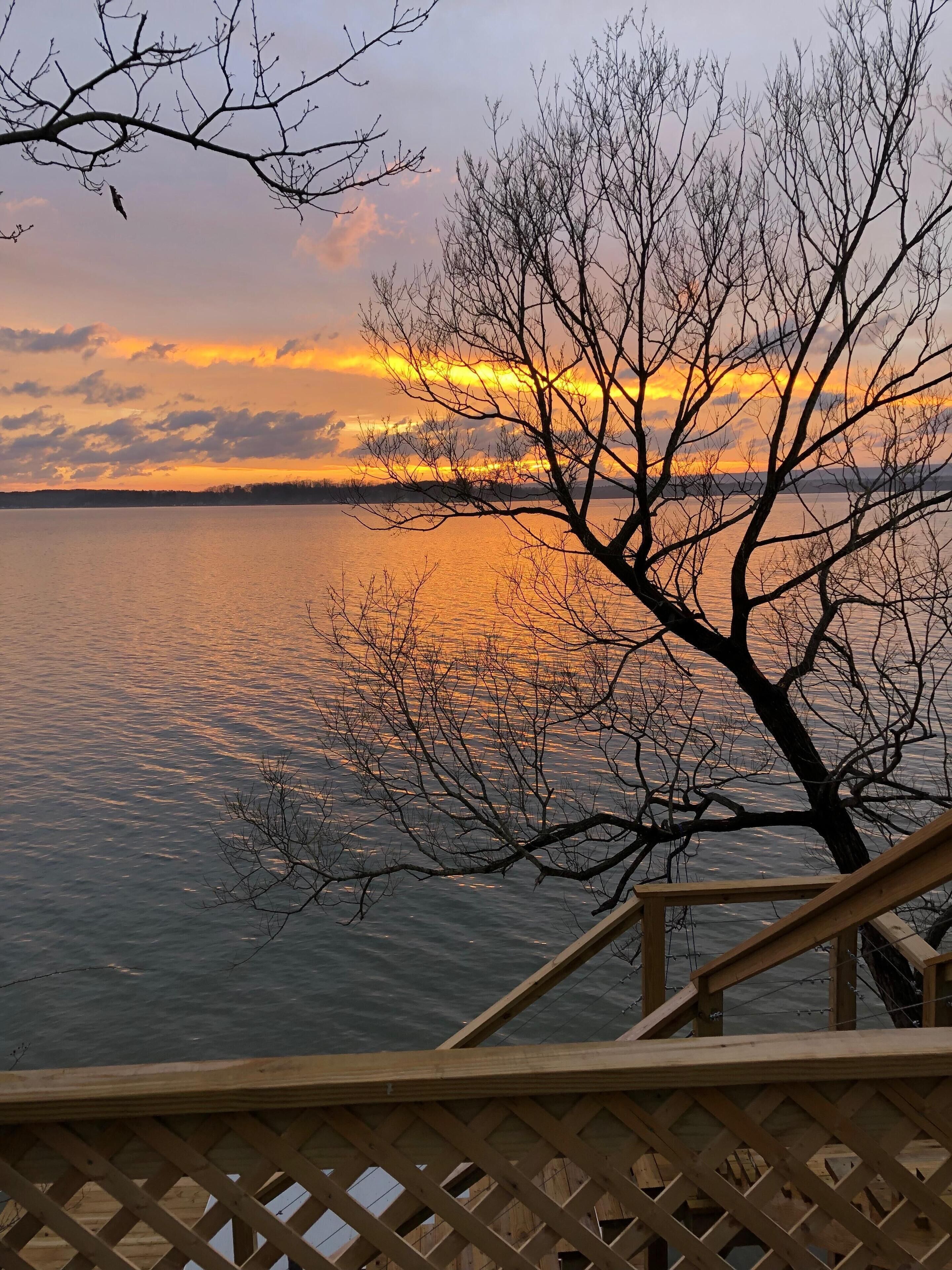 A wooden deck with a view of a body of water and a sunset.