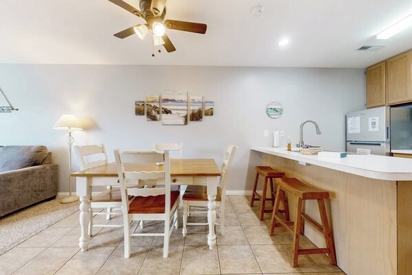 A modern kitchen with a dining area, a ceiling fan, and a refrigerator.