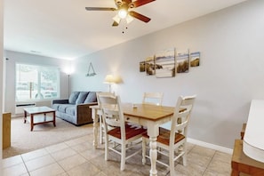 A dining area with a wooden table and chairs, a ceiling fan, and artwork on the wall.
