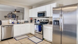 Eine moderne Küche mit weißen Schränken, Edelstahlgeräten, einer Mikrowelle, einem Backofen und einem Kühlschrank.