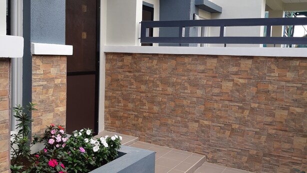 A modern building with a stone facade, a metal gate, and a small garden with flowers. - Restful 3BR Hillside Duplex (Baguio)