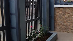 A gated entrance with a metal fence and a stone wall. - Restful 3BR Hillside Duplex (Baguio)