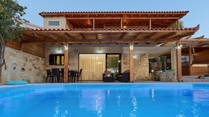 A swimming pool with a wooden pergola and stone walls. - Feronia Villas (Hersonissos)