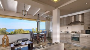 A modern living room with a dining area, a kitchen, and a balcony with a view of the sea. - Feronia Villas (Hersonissos)