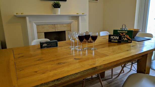 Una mesa de comedor de madera con una caja de 'After Dinner Trivia' y un juego de cartas y dados 'Kummikw'.