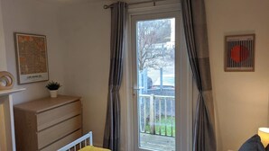 Una habitación con un aparador de madera, una planta pequeña, un mapa de Los Ángeles y un ventanal con cortinas.