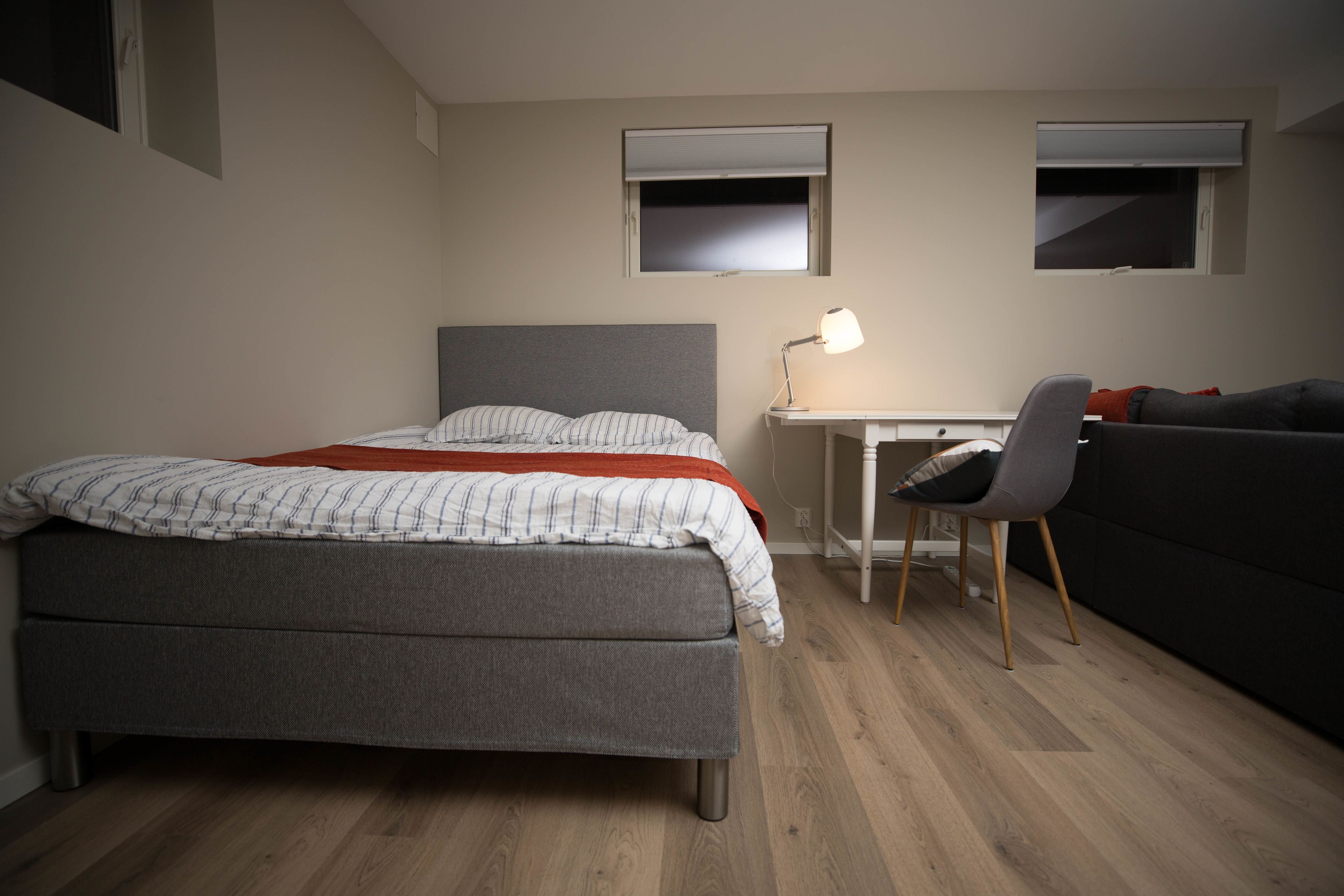 Ein Schlafzimmer mit Bett, Schreibtisch, Stuhl und einer Couch.