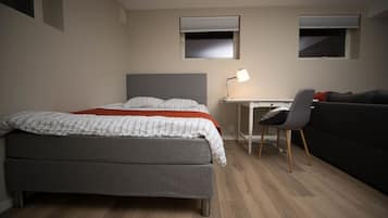 Ein Schlafzimmer mit Bett, Schreibtisch, Stuhl und einer Couch.