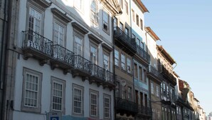 A row of historic buildings with balconies, a clear blue sky, and a parking sign. - Merc Porto Ribeira View (Porto)