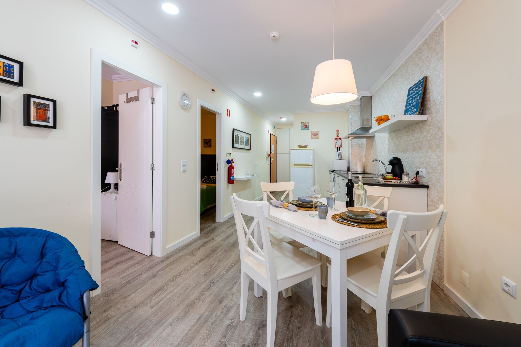 A modern kitchen with white cabinetry, a dining table with chairs, and a hanging light fixture.