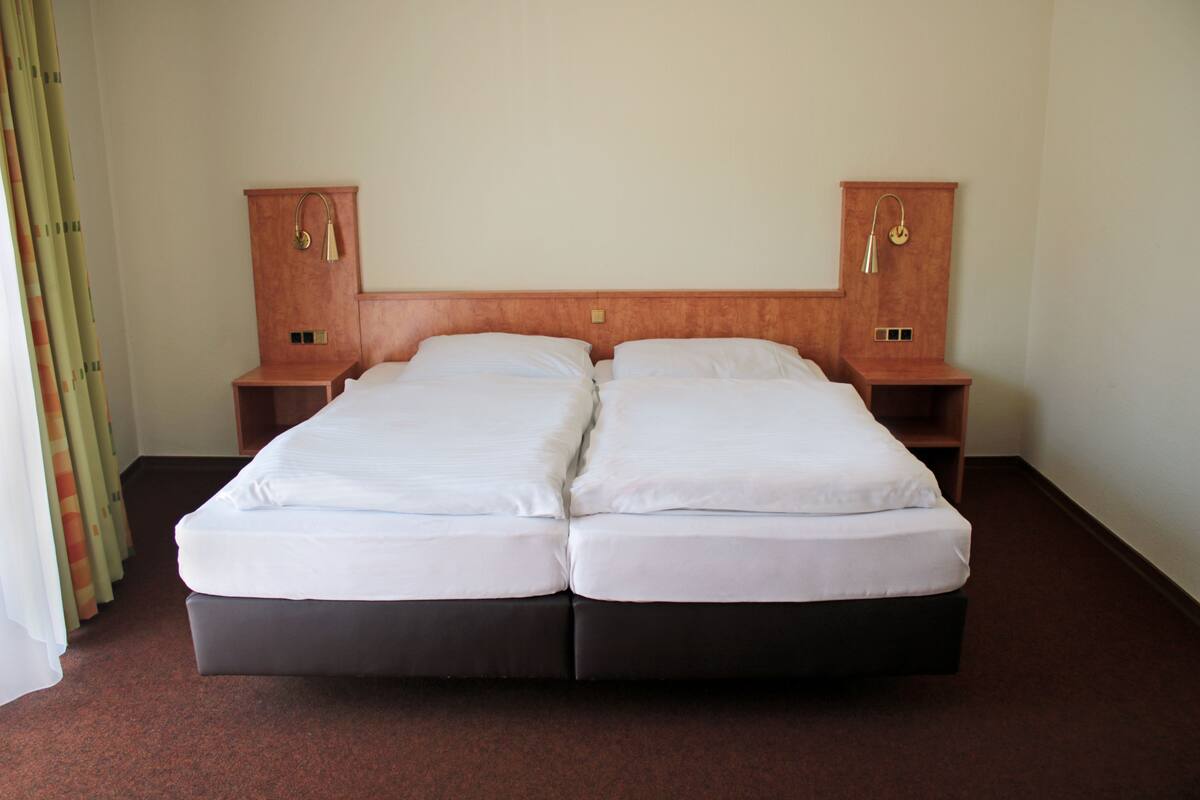 A double bed with a wooden headboard, two bedside tables, and a carpeted floor.