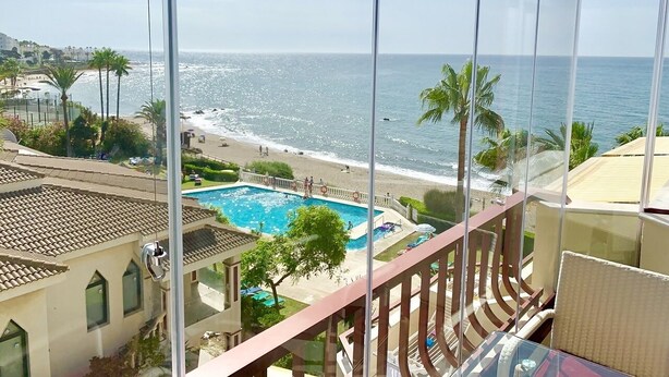 Un balcón con vistas a la playa y una piscina.