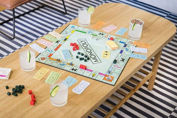 Un plateau de jeu de Monopoly posé sur une table en bois, avec des dés, des pions et des billets de banque.
