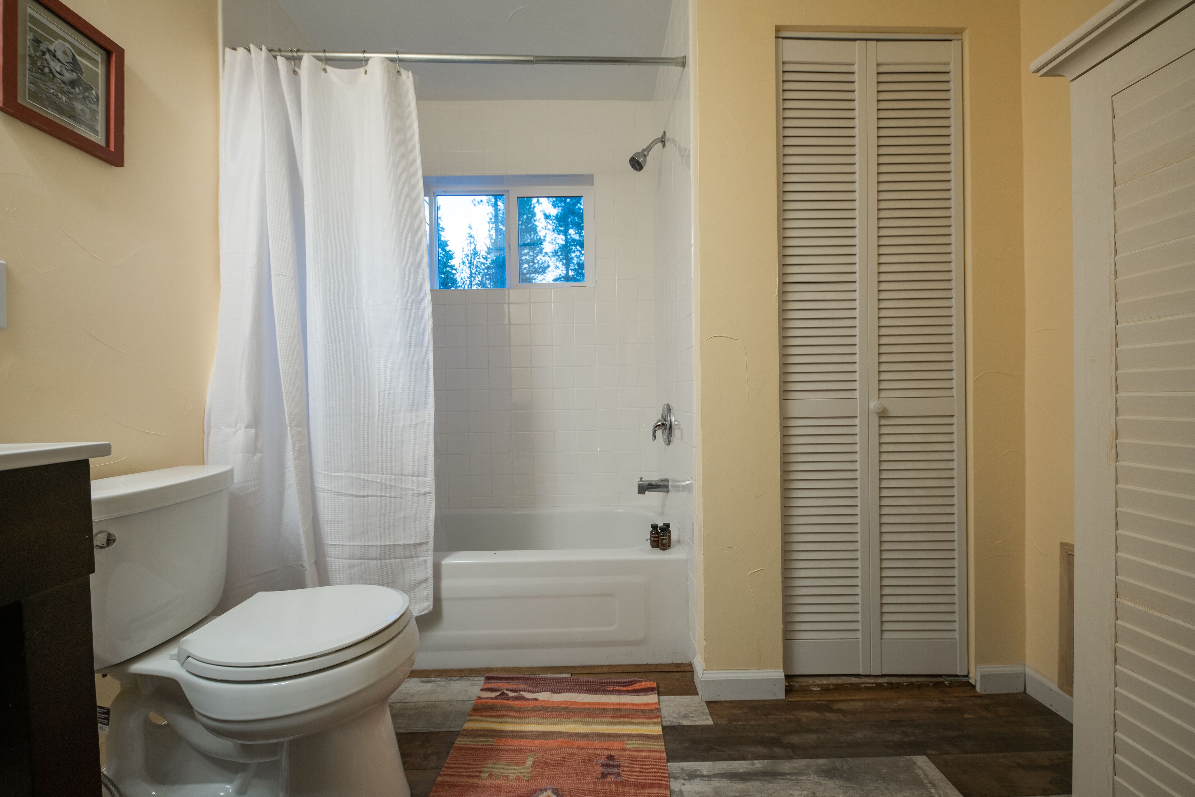 A bathroom with a toilet, bathtub, and a window.