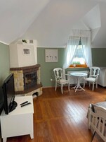 Una habitación acogedora con chimenea, una mesa de comedor con sillas, un televisor y una ventana con cortinas.