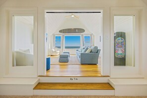 Un salon spacieux avec vue sur l’océan, un ventilateur de plafond et une décoration originale avec des planches de skate colorées.