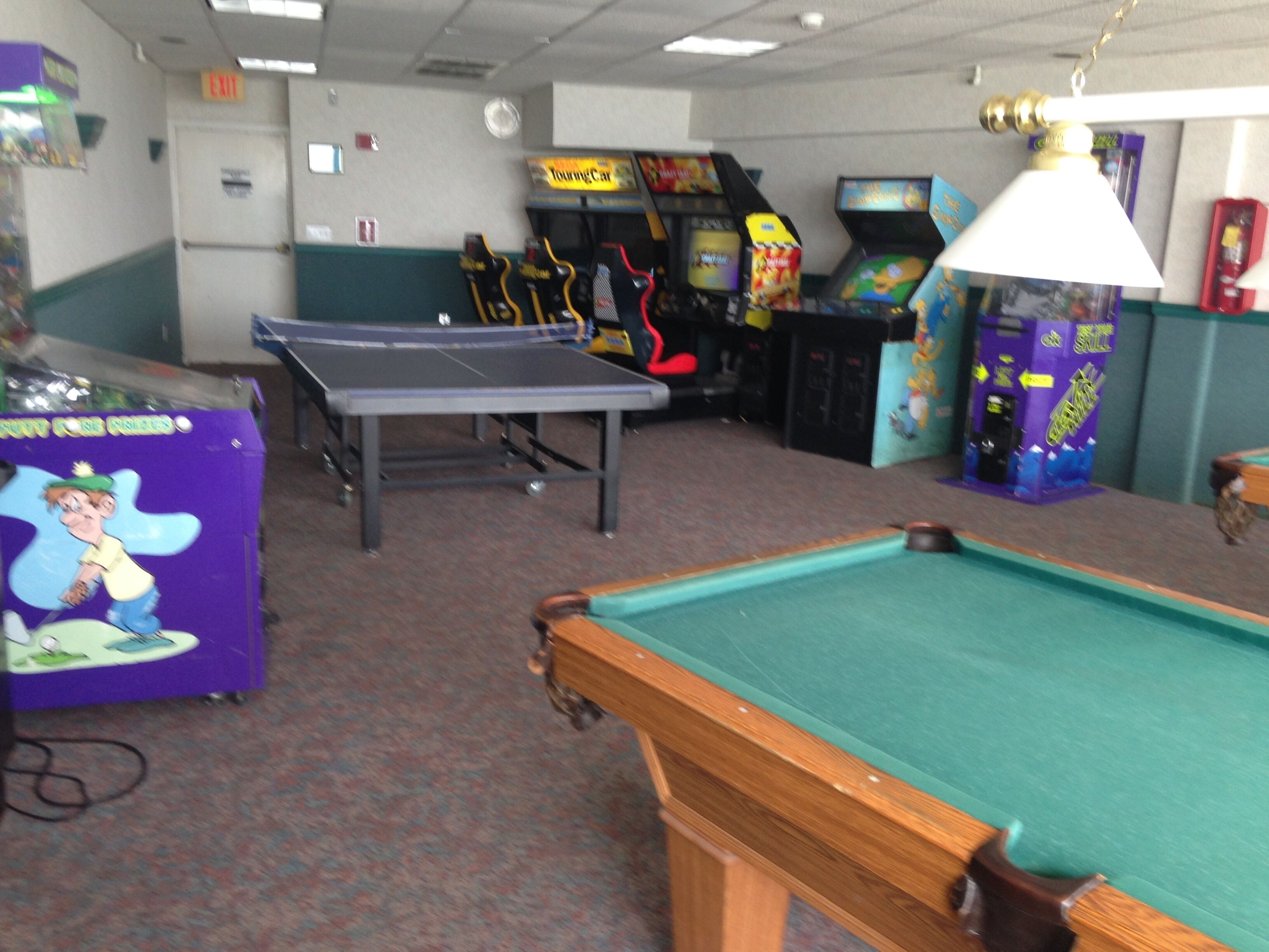 A room with a pool table, arcade games, and a ping pong table.