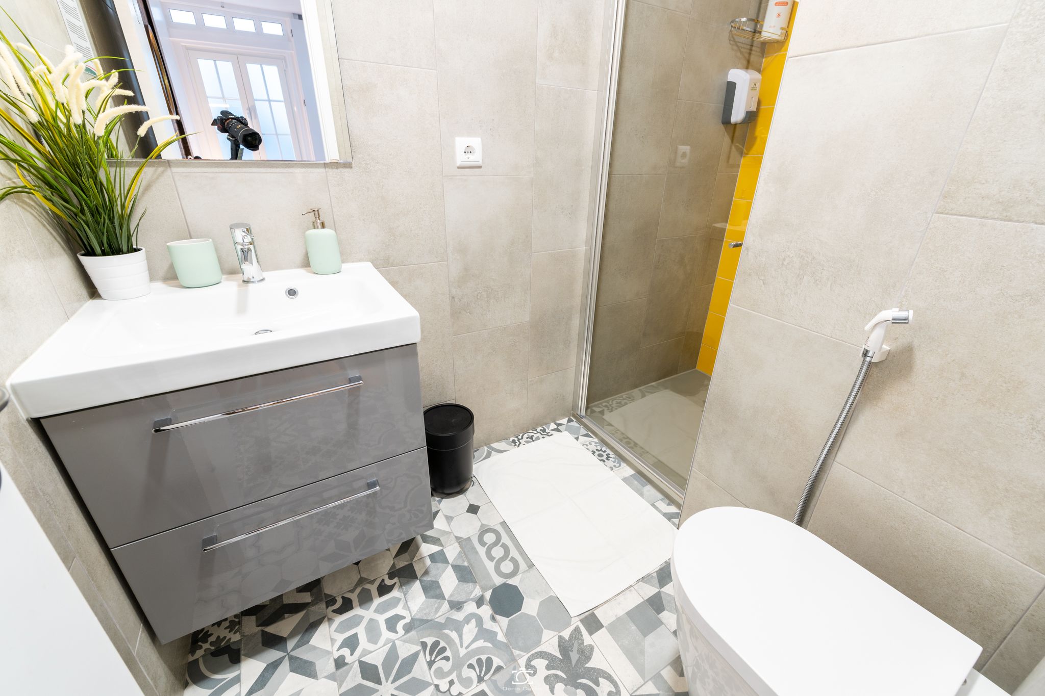 Une salle de bain moderne avec un lavabo blanc, un meuble gris et un espace douche.
