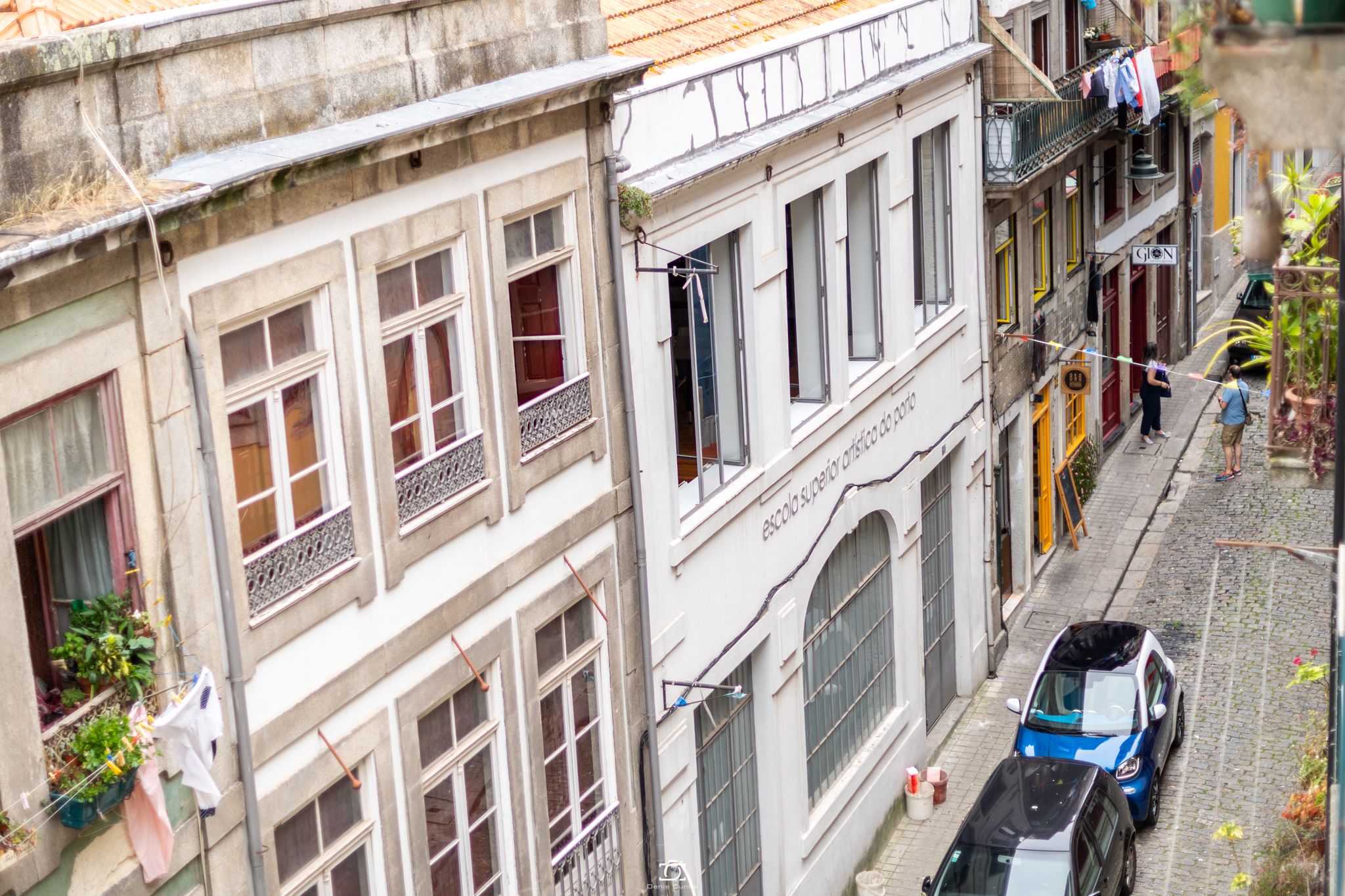 A narrow street with buildings featuring balconies and windows.