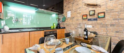 A modern kitchen with a brick wall, wooden cabinets, and a dining area set for six.