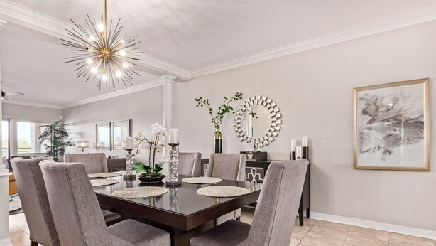 Comedor con una mesa de madera oscura, sillas tapizadas en gris y una lámpara de techo moderna.