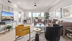 Un salón espacioso con televisión de pantalla plana, asientos cómodos, una mesa de centro y un ventanal con vistas al exterior.