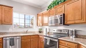 Una cocina con armarios de madera, electrodomésticos de acero inoxidable, un ventanal con vistas y una encimera de granito.