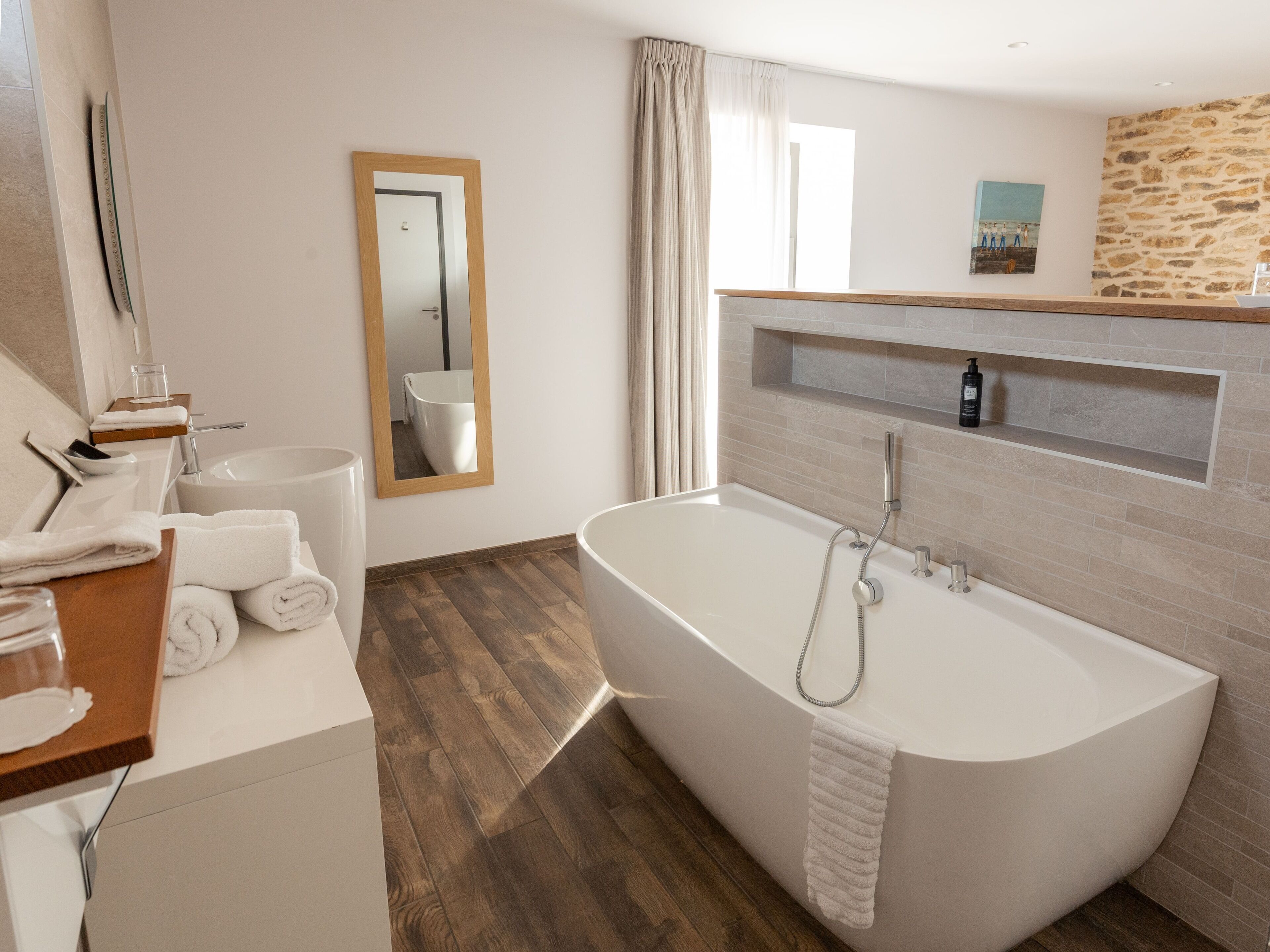 A modern bathroom with a freestanding bathtub, a mirror, a sink, and a shower.