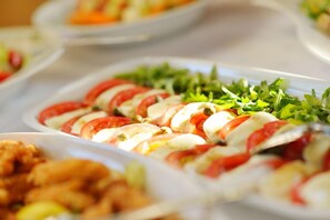 A buffet with various dishes, including a salad with tomatoes and greens, and other food items.