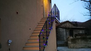 A house with a staircase leading to a balcony, decorated with blue and green lights. - Podere Groppini (Fivizzano)