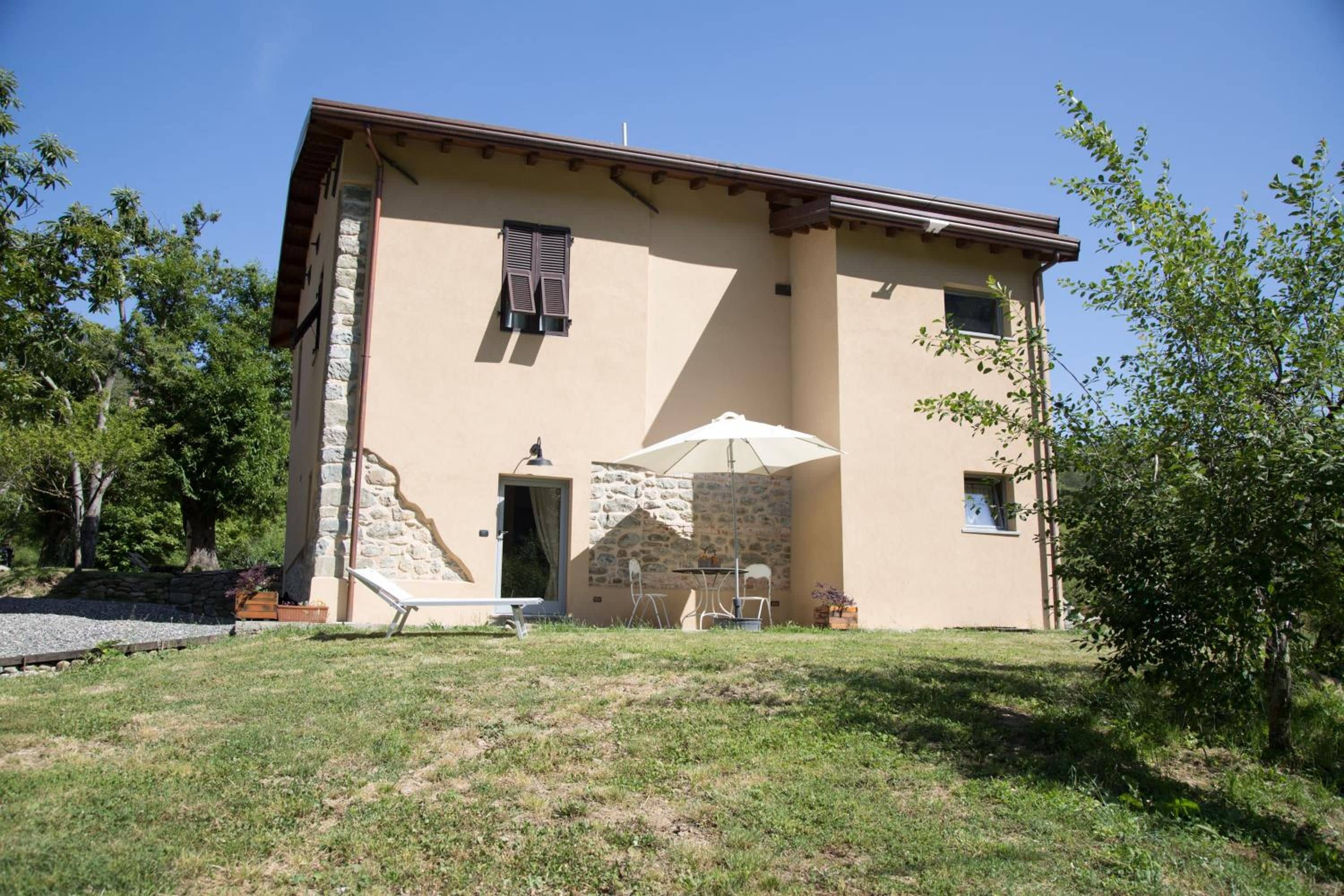 A two-story building with a stone facade, a door, and a small patio with a table and chairs.