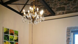 A cozy room with a red-striped sofa, a chandelier, a dining table with chairs, and a stone wall. - Podere Groppini (Fivizzano)