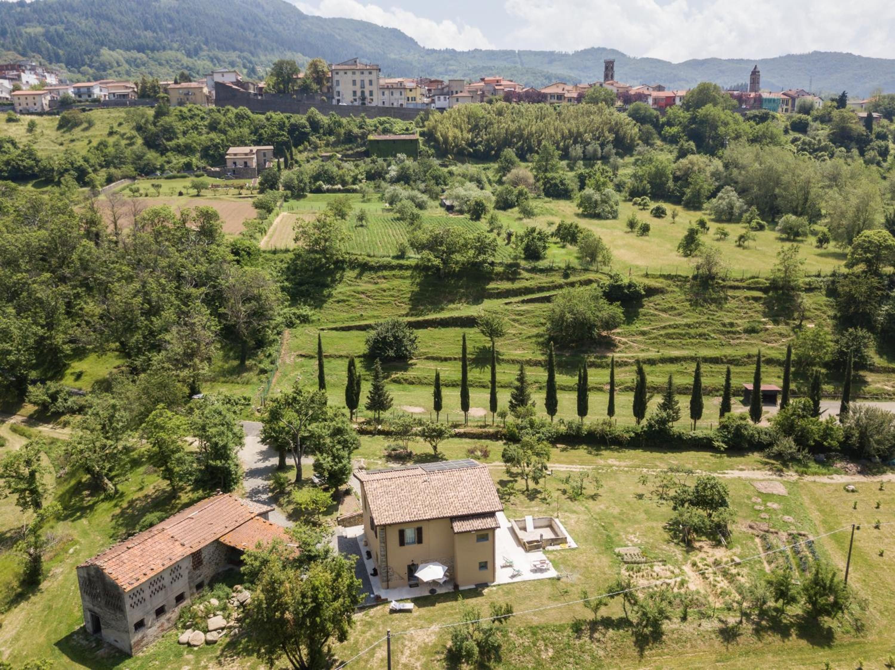Ländliche Landschaft mit terrassenförmig angelegten Feldern, einem kleinen Gebäude mit Ziegeldach und einem Dorf in der Ferne.