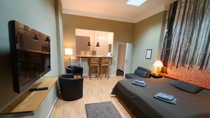 Une chambre d’hôtel moderne dotée d’un grand lit, d’une télévision à écran plat, d’un bureau avec des chaises et d’un coin repas.
