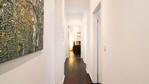 Un couloir avec une grande carte accrochée au mur gauche, un plancher en bois et une porte au fond.