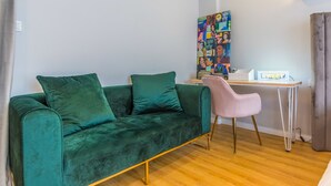 A room with a green velvet sofa, a pink chair, a desk with a computer, and a colorful artwork on the wall. - Shanghai Moxi Inn Huaihai Rd No.6 Branch (Shanghai)