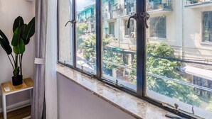 A room with a large window, wooden flooring, a small table, and a potted plant. - Shanghai Moxi Inn Huaihai Rd No.6 Branch (Shanghai)