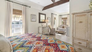 A bedroom with a large bed, a dresser, a chair, and a wardrobe.