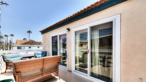 A balcony with wicker furniture, sliding glass doors, and a clear view of the surrounding area.